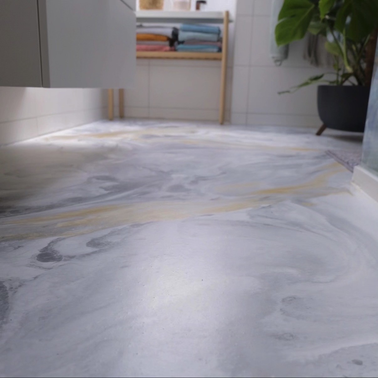 Custom marbled epoxy floor with gold accents in a residential bathroom